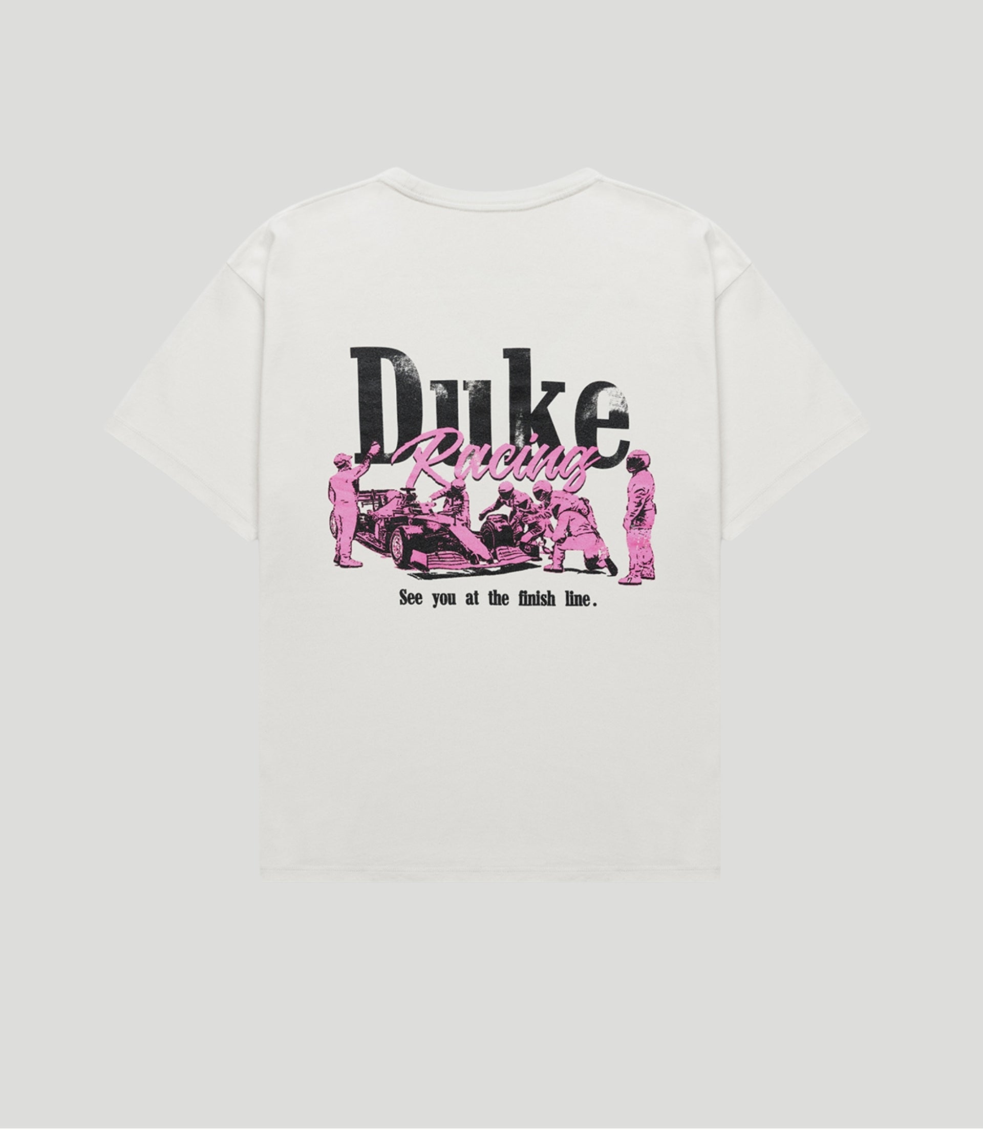 Back view of a white vintage T shirt with large black Duke text and pink Racing script beneath a racing scene.