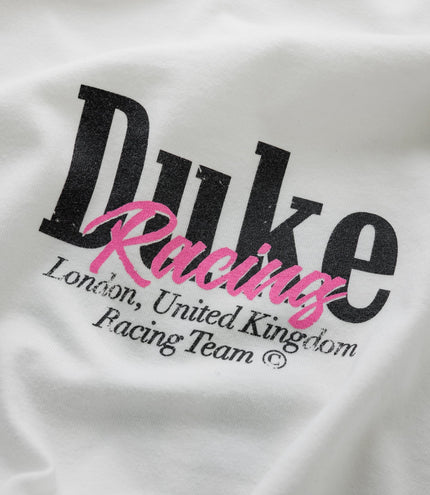 Close up of white fabric with bold black Duke lettering and bright pink Racing script across the print.