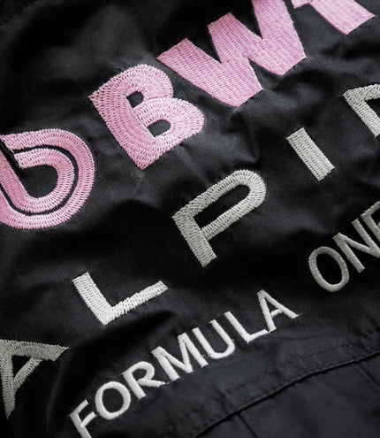 Patch with large pink embroidered lettering on black jacket fabric