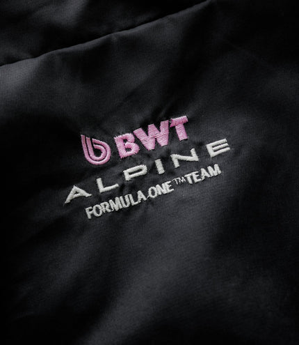 Close-up of black fabric showing pink BWT Alpine embroidery and white Duke & Dexter branding on the jacket