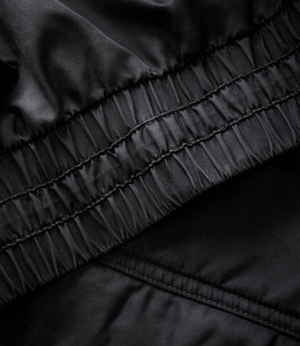 Close-up of black quilted sleeve with elastic and stitched panels on the trackside jacket