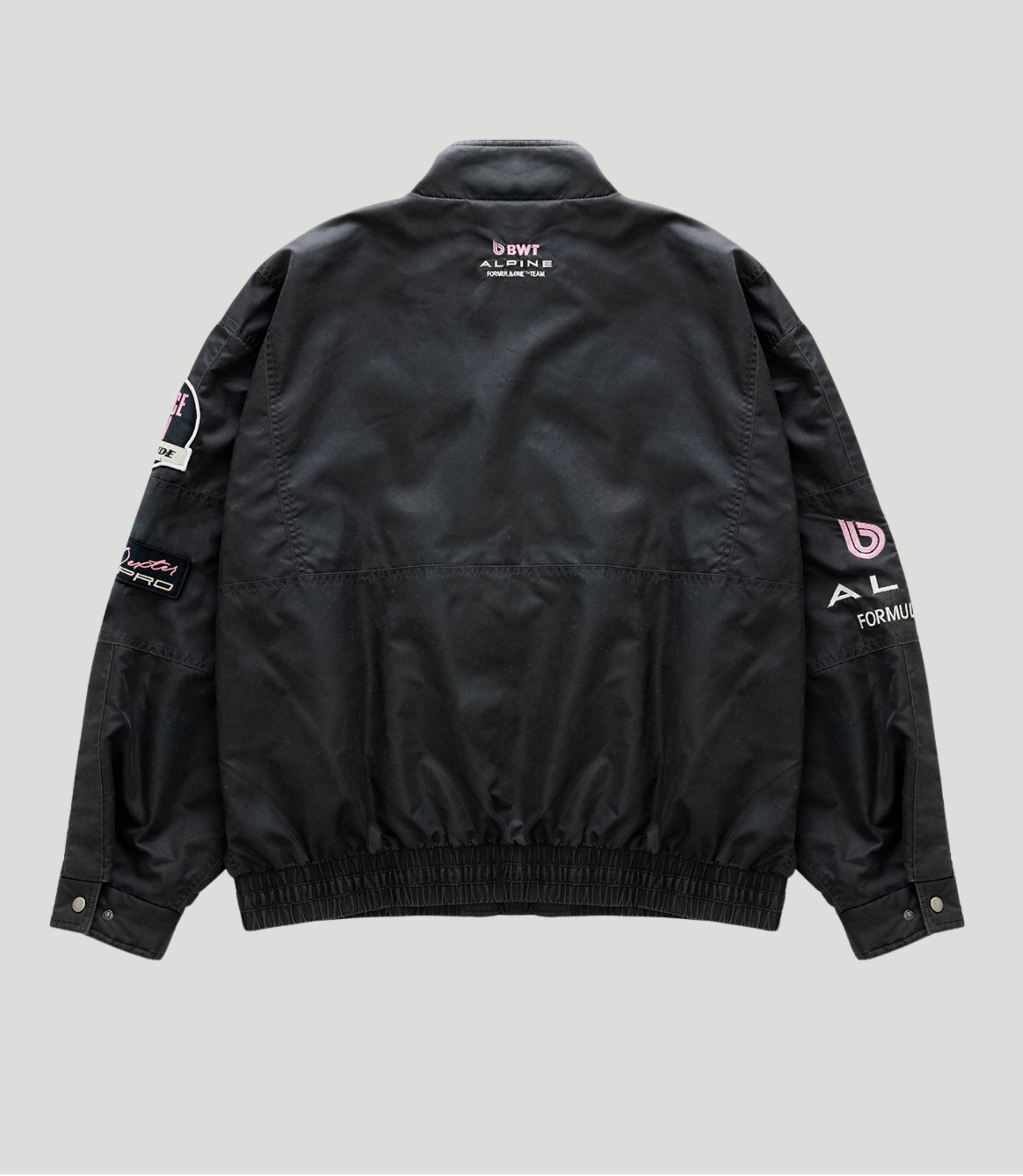 Back view of black trackside jacket with pink BWT Alpine logo and Alpine Formula One Team text.
