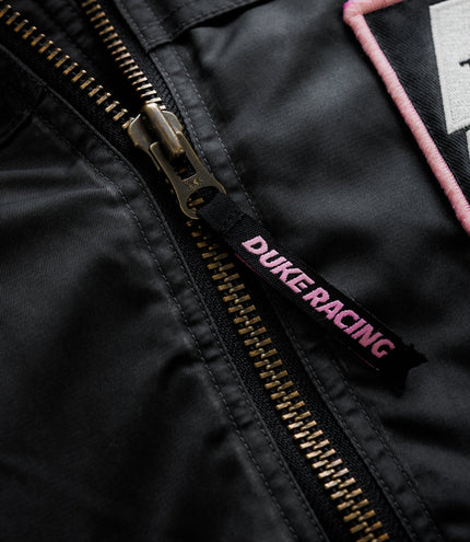 Brass zipper with pink piping and Duke & Dexter label on black trackside jacket