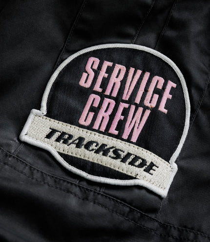 Round embroidered patch with pink text on black fabric