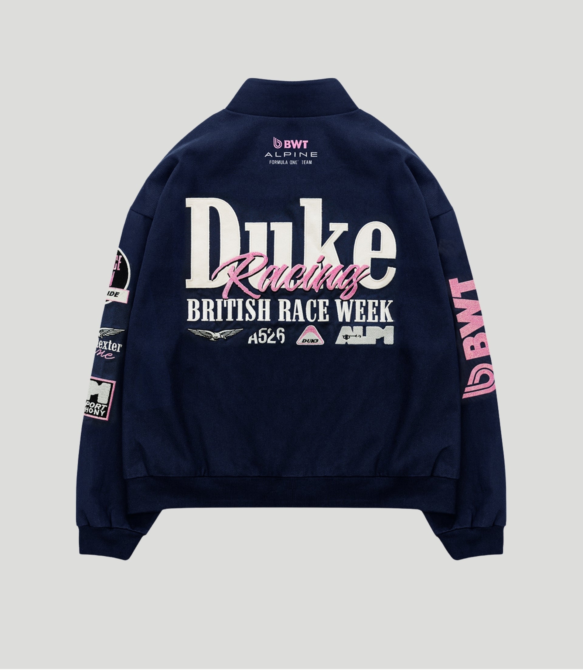 Back view of navy racing jacket with large white Duke lettering and pink racing script and BWT Alpine logo
