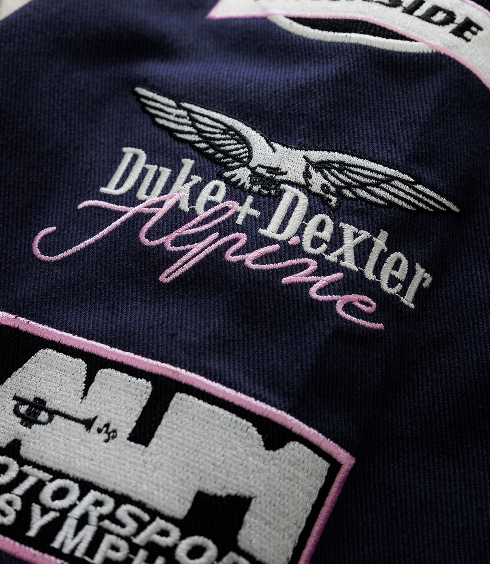 Duke & Dexter racing patch outlined in pink on navy fabric with finish line graphic