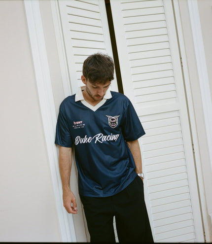 Male model wearing navy blue BWT Alpine Formula One Team Duke & Dexter jersey with white collar and crest