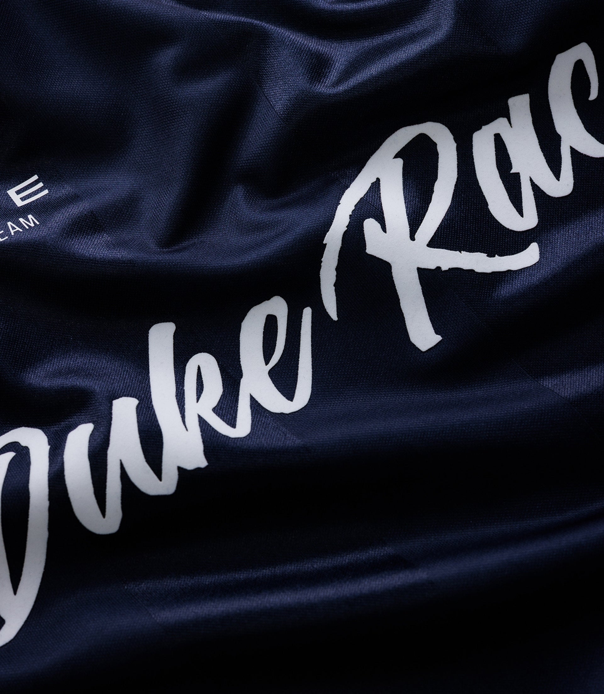 Close up of navy jersey fabric showing large white script text and Alpine branding