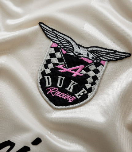 Close up of embroidered Duke Racing patch with wings and checkered design on satin fabric