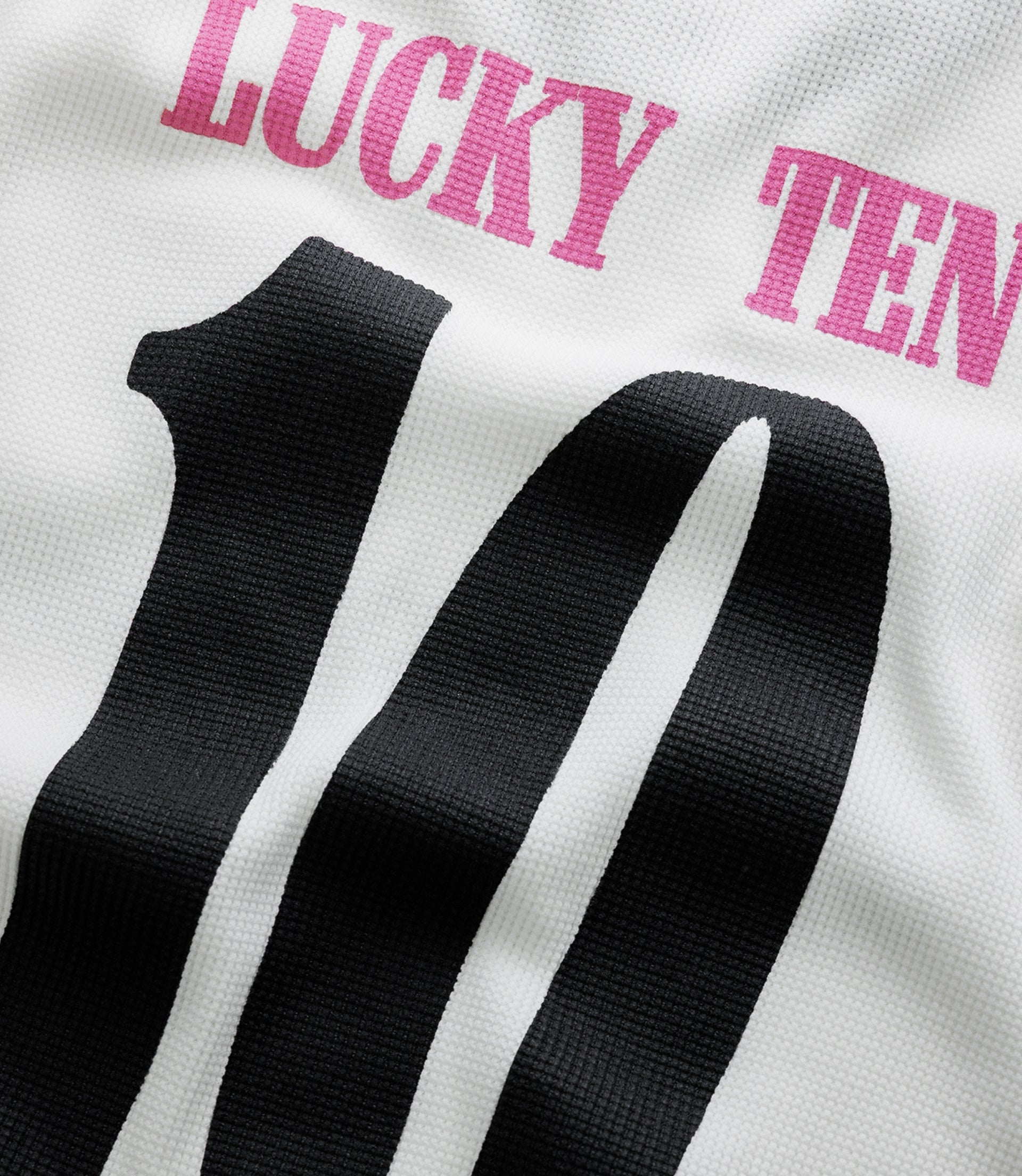 White fabric with bold pink racing team lettering and patches visible on the chest area.