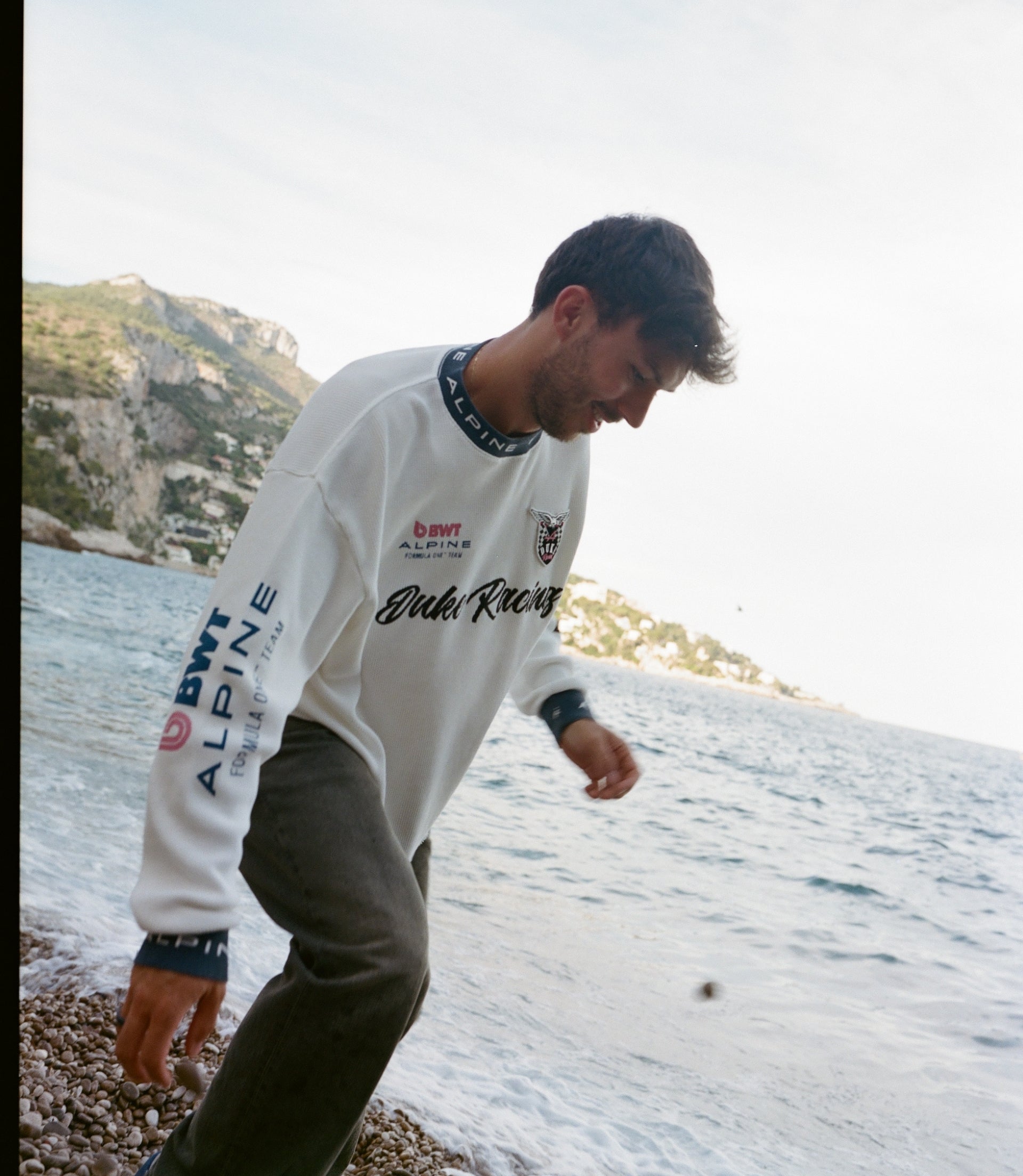 Man wearing white Duke & Dexter waffle jersey with BWT Alpine branding at a rocky seaside