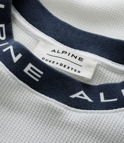 Close up of white waffle fabric with a navy Duke & Dexter strap and an Alpine label