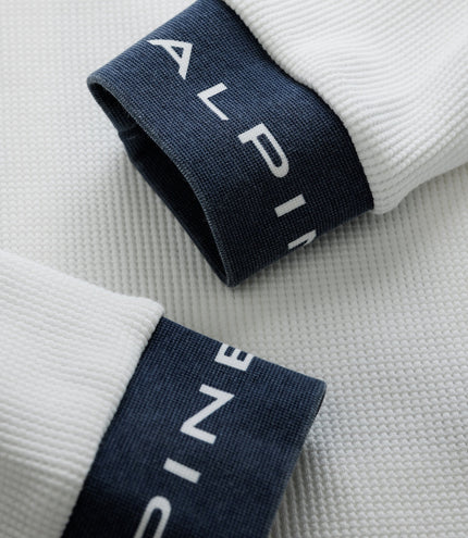 Close up of white waffle knit sleeve with a dark blue cuff featuring white Duke branding.