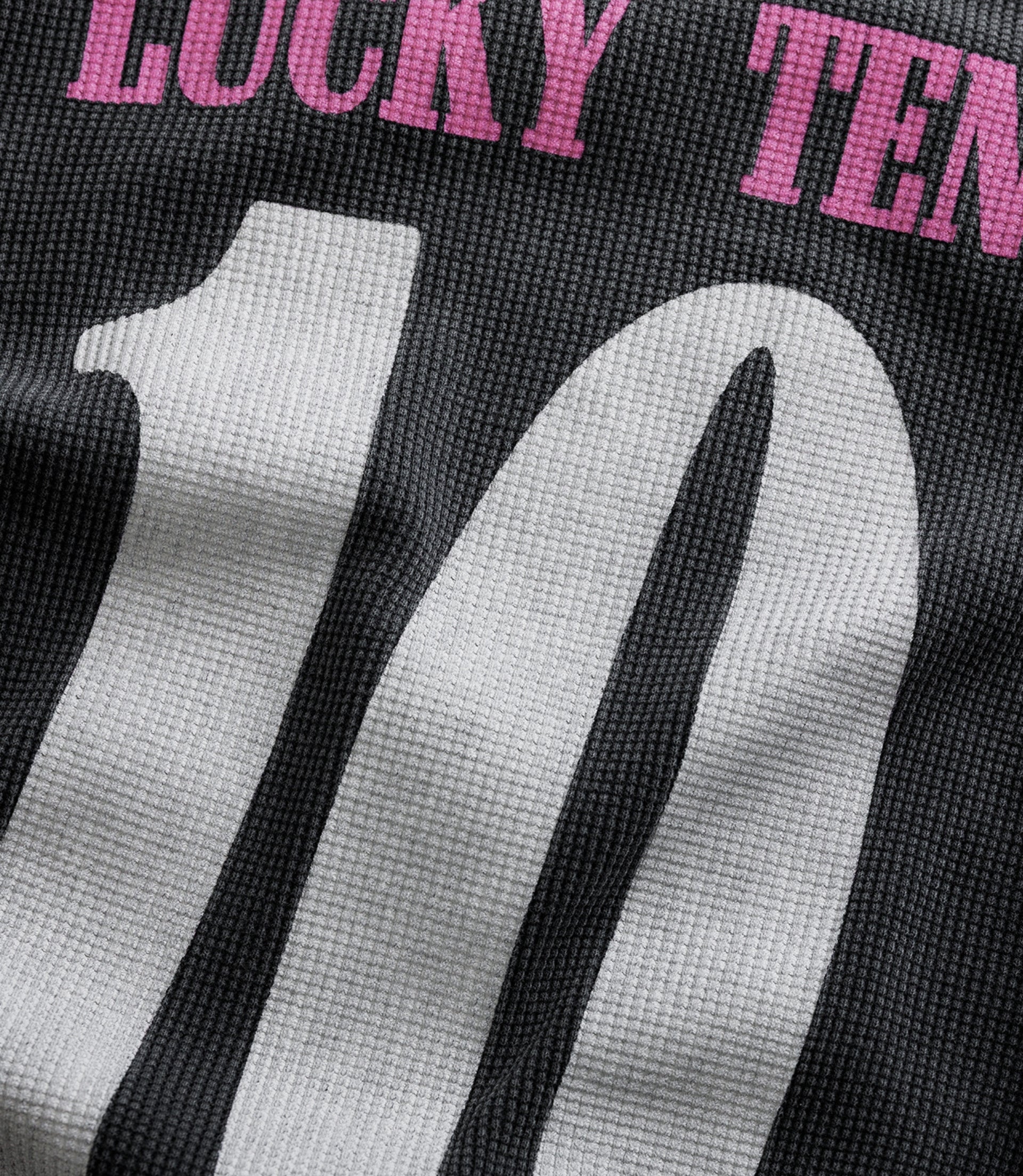 Close up of black waffle knit fabric from the unisex BWT Alpine racing jersey with pink lettering