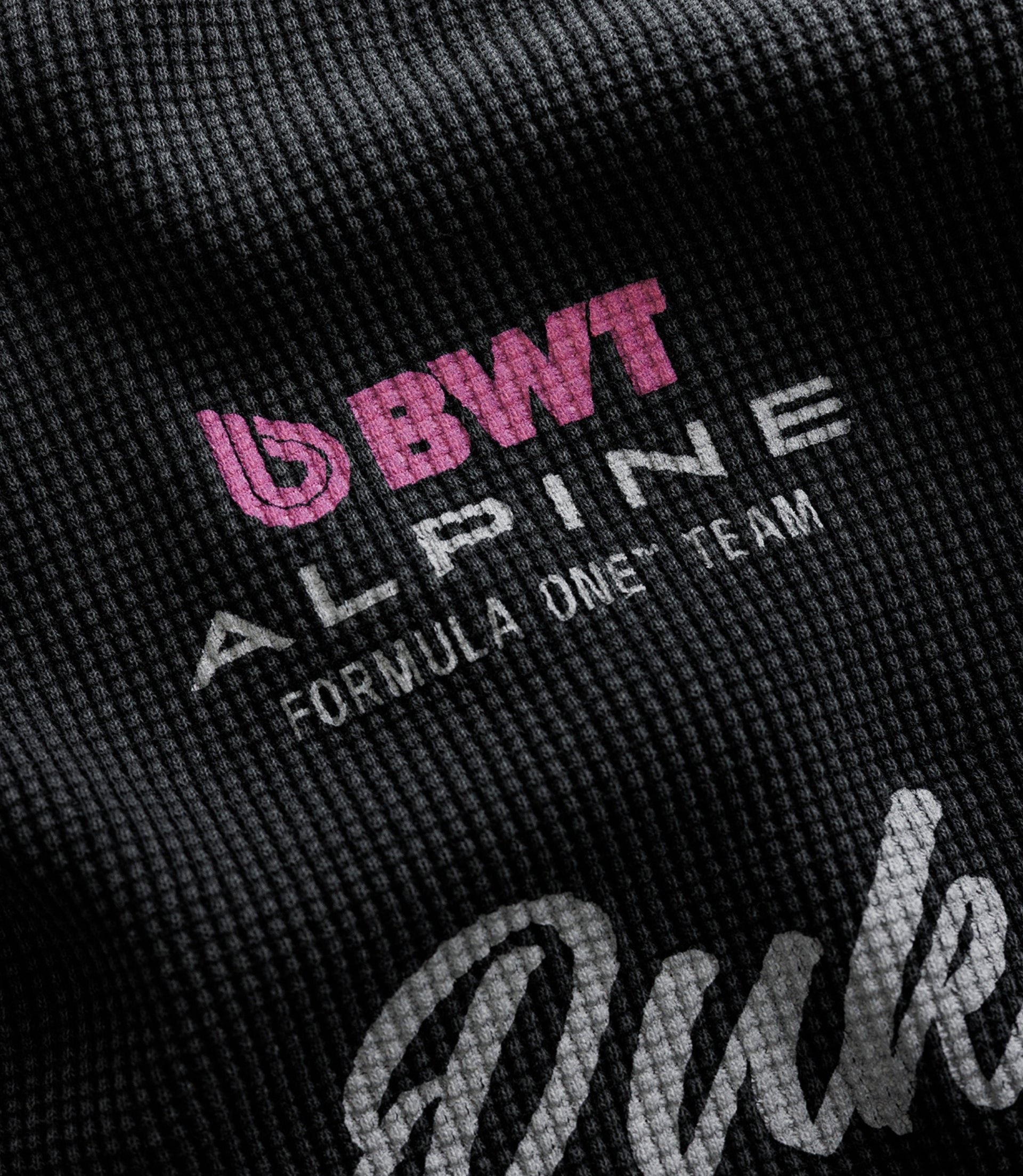 Close-up of black waffle fabric featuring pink BWT Alpine Formula One Team branding.