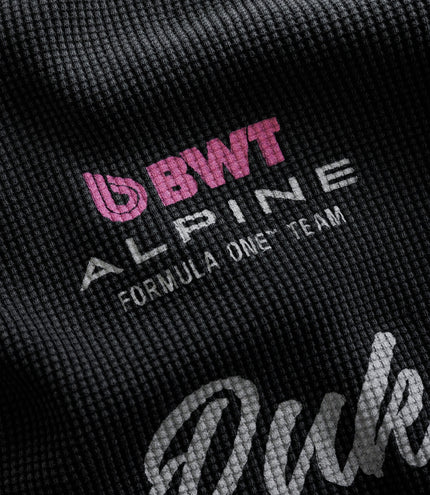 Close-up of black waffle fabric featuring pink BWT Alpine Formula One Team branding.