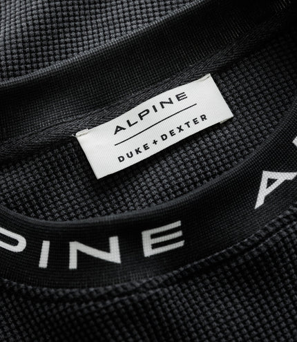 White tag reading ALPINE DUKE & DEXTER sewn into black jersey.