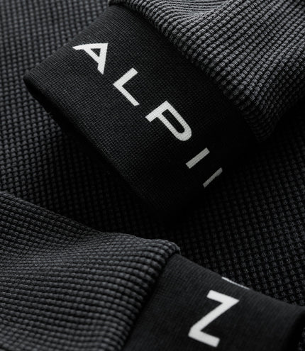 Close-up of black ribbed sleeve cuff with white Alpine logo on the jersey
